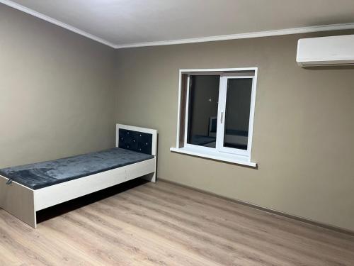 a bedroom with a bed and a window at Дачный дом in Balqash
