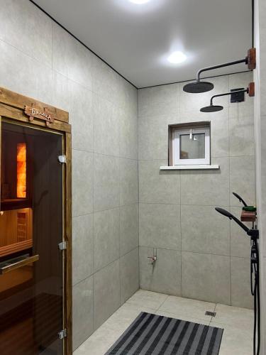 a room with a shower with a door and a window at Дачный дом in Balqash