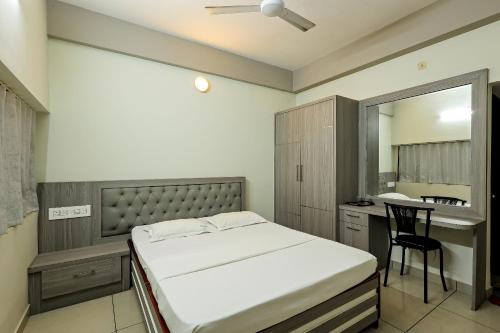 a bedroom with a bed and a desk and a mirror at Landmark INN in Kāsaragod