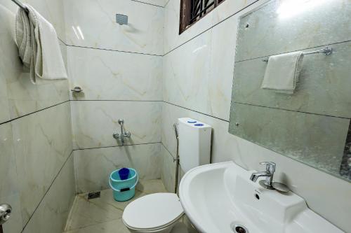 a white bathroom with a toilet and a sink at Landmark INN in Kāsaragod