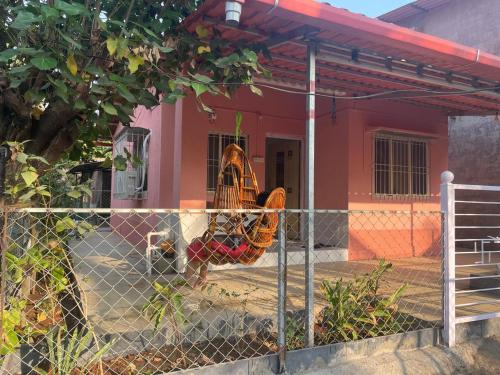 a fence in front of a red house with a baseball glove at Golden Wave Cottage in Revadanda