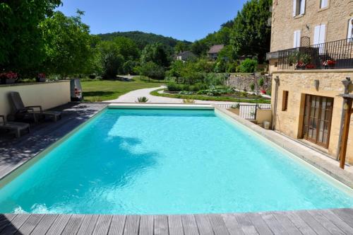 een groot zwembad met blauw water in een tuin bij Les Terrasses de Daglan in Daglan