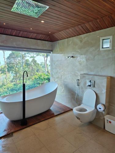 a bathroom with a bath tub and a toilet at The Cozy Clouds Hill Stay in Napoklu