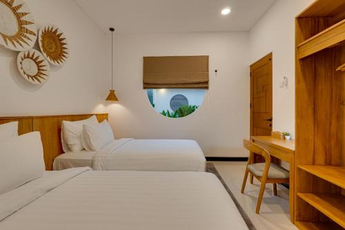 a hotel room with two beds and a desk at Bhatara Villa Sanur in Sanur