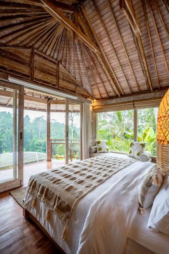 a bedroom with a large bed with a large window at Moonlit Jungle in Seribatu