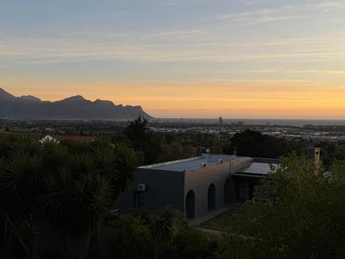 une vue d'une maison avec le coucher de soleil en arrière-plan dans l'établissement Luxe Stay Somerset West 4, à Somerset West