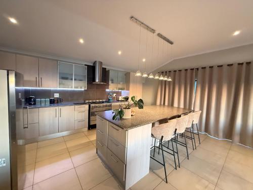 une cuisine avec un îlot et des tabourets de bar dans l'établissement Luxe Stay Somerset West 4, à Somerset West