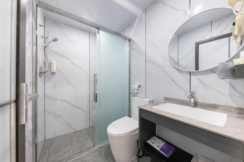 a bathroom with a toilet and a sink and a mirror at Good East Hotel in Guangzhou