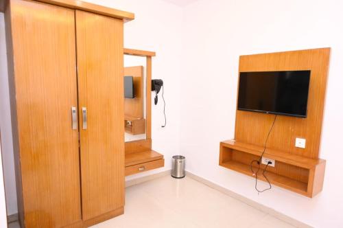 a living room with a tv and a wooden cabinet at Hotel Kailash Heaven in Madikeri