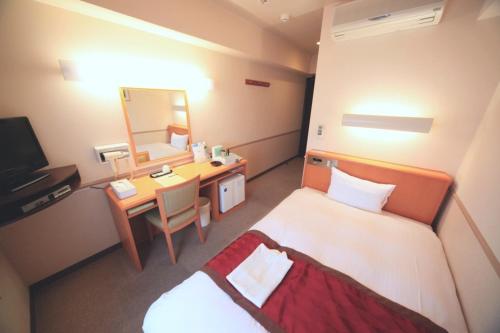土浦市にあるCrown Hills Tsuchiuraekihigashiのベッド、鏡付きのデスクが備わるホテルルームです。