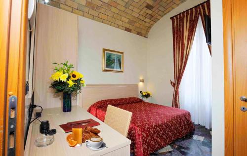 a bedroom with a bed and a table with a vase of flowers at Hotel Campidoglio in Rome