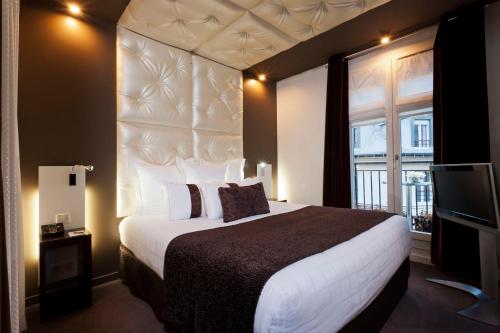 - une chambre avec un grand lit et une télévision dans l'établissement Grand Hotel Saint Michel, à Paris