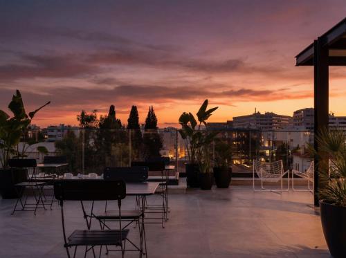 a rooftop patio with tables and chairs at sunset at Aweso Limassol in Limassol