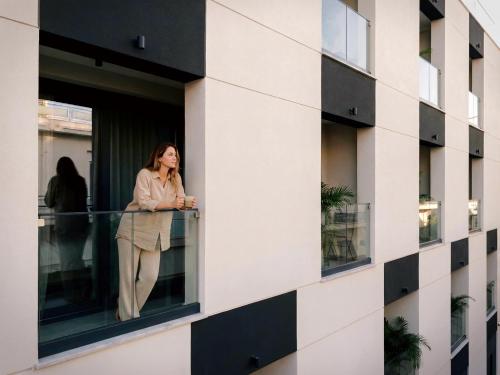 a woman standing on a balcony of a building at Aweso Limassol in Limassol