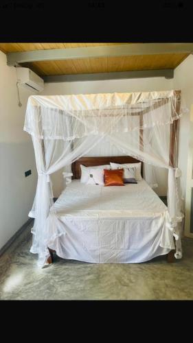 a bedroom with a white bed with a canopy at Calm Villa in Mihiripenne