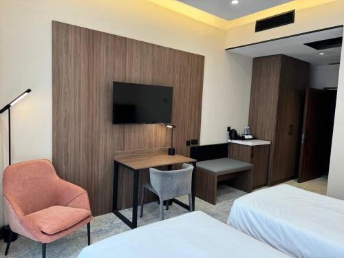 a hotel room with a desk and a tv on a wall at Afrosiyob Regency Hotel in Stantsiya Kyzyl-Tukumachi
