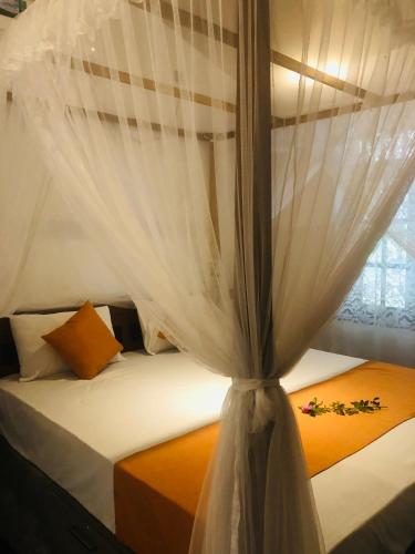 a bedroom with a bed with a curtain on it at Coco Breeze Villa in Talpe