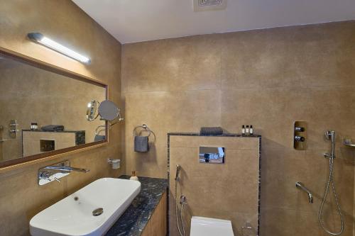 een badkamer met een wastafel, een toilet en een spiegel bij Astara Munnar in Munnar