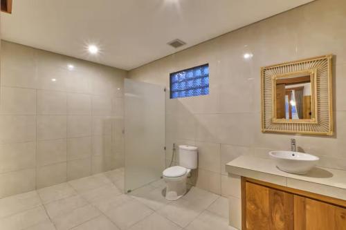 een badkamer met een toilet, een wastafel en een spiegel bij Long Lane Bali Villa in Ubud