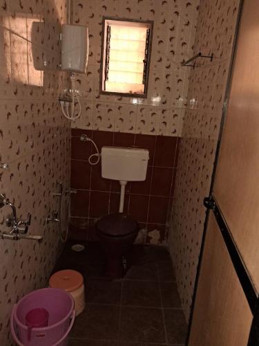 a small bathroom with a toilet and a window at Hotel Cosy Nook in Malvan