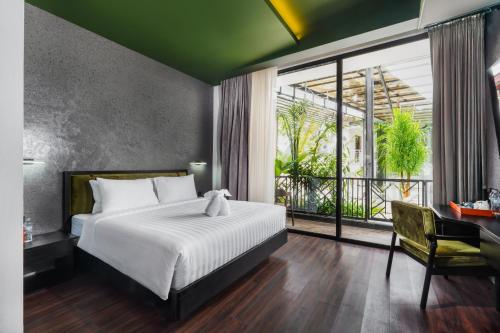 een slaapkamer met een bed en een groot raam bij Maha Resort Bali in Pererenan