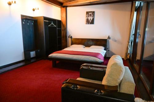 ein Schlafzimmer mit einem Bett, einem Stuhl und einem Koffer in der Unterkunft Casa Frent in Predeal