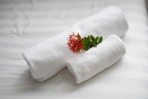 deux serviettes blanches avec une fleur rouge dessus dans l'établissement BlueHome Apartment, à Vientiane