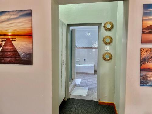 a hallway with a door leading into a bathroom with paintings at Dreamers Guesthouse - NO LOADSHEDDING in King Williamʼs Town