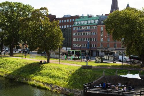 a group of people sitting in a park next to a river at Moment Hotels in Malmö