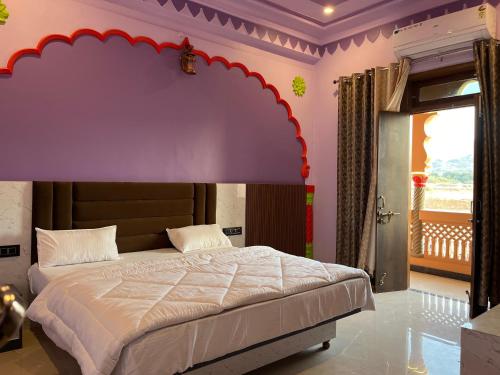 een slaapkamer met een groot bed met een paars hoofdeinde bij Hotel Simran Desert View Haveli in Pushkar
