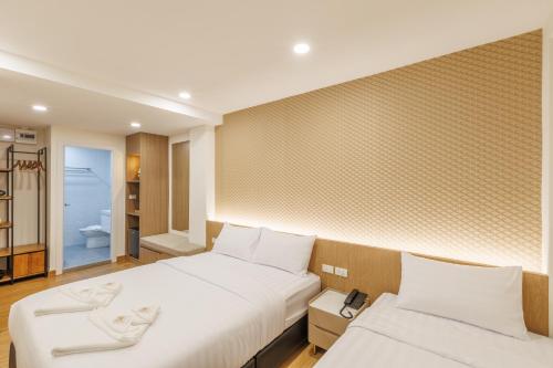 ein Schlafzimmer mit zwei Betten und ein Badezimmer in der Unterkunft Believeinn in Bangkok