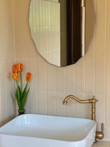 a bathroom with a sink and a mirror and flowers at Sayu Homestay&Cafe in Ban Pha Mi