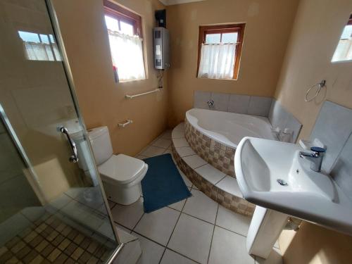 a bathroom with a tub and a toilet and a sink at Tevreden in Rhodes
