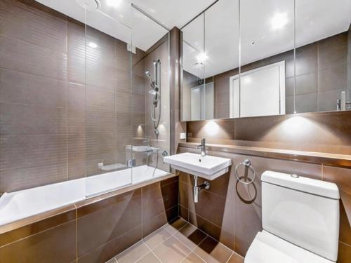 a bathroom with a toilet and a sink and a mirror at Sydney Olympic Park 13Free Parking in Sydney