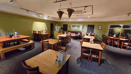 a restaurant with wooden tables and chairs and a room with tables at Carramar Motor Inn in Palmerston North