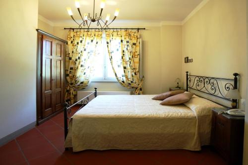 ein Schlafzimmer mit einem Bett mit einem Kronleuchter und einem Fenster in der Unterkunft Golf Club Bellosguardo resort in Vinci