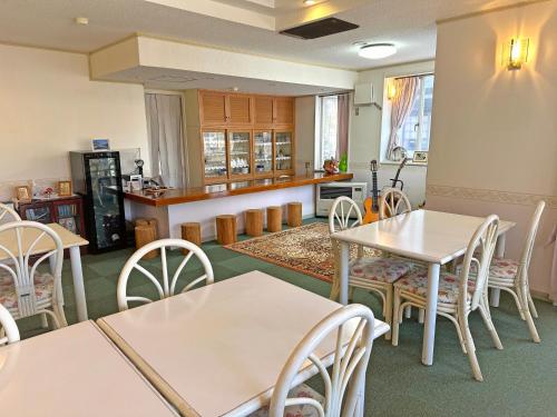 a dining room with white tables and chairs at ペンション風と旅のアトリエ in Tateshina
