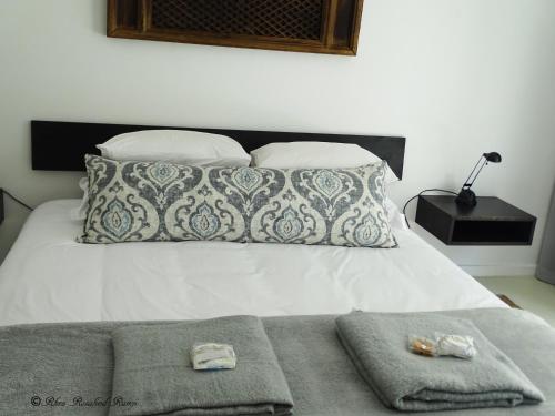 a bed with two pillows and towels on it at Agulhas Ocean House in Agulhas