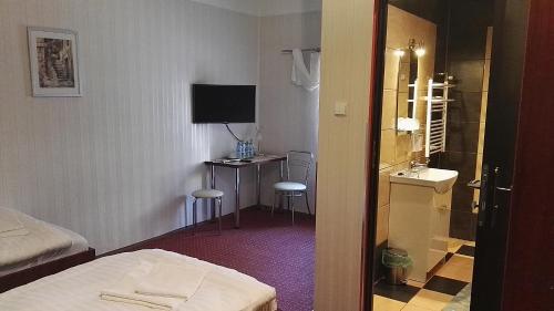 Pokój hotelowy z łóżkiem i biurkiem z umywalką w obiekcie Karczma pod Młynem w mieście Katowice