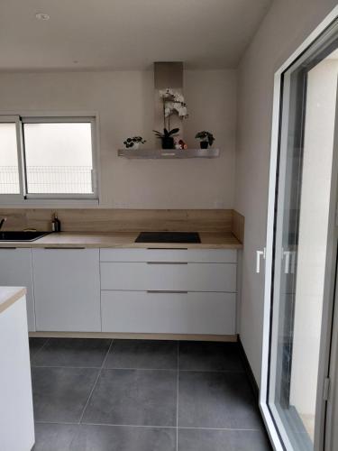 een keuken met witte kasten en een raam bij Gîte du champ aisé in Montaigu-Vendée