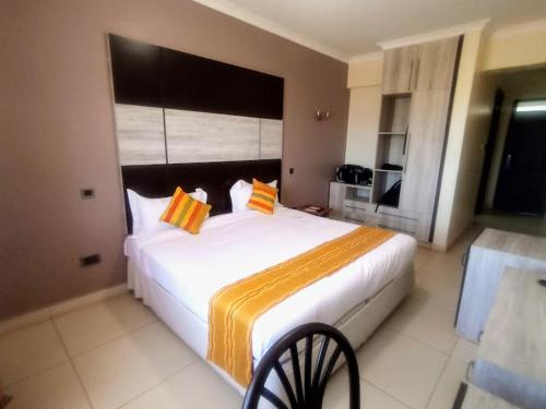 a bedroom with a large white bed with orange pillows at Saala Hotel Limited in Gatunga