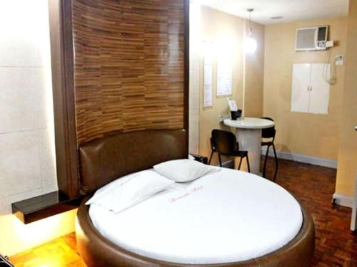 ein Schlafzimmer mit einem großen Bett und einem Tisch in der Unterkunft Bermuda Hotel in Manila