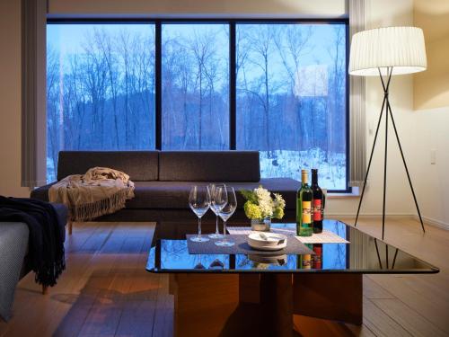 a living room with a couch and a table with wine glasses at Minn house Niseko Hirafu in Kutchan