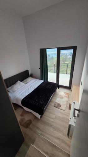 a bedroom with a bed and a large window at Forest Edge Lake House in Desmerice
