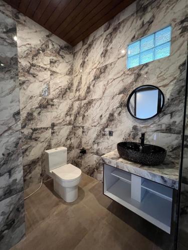 een badkamer met een toilet, een wastafel en een spiegel bij Adiuma Cottage Ubud in Ubud