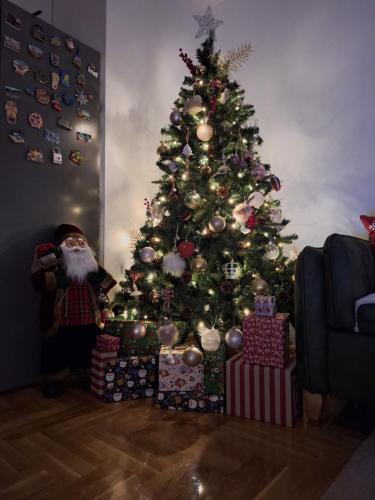 een kerstboom met cadeautjes eronder in een woonkamer bij Apartman Fenix in Pirot
