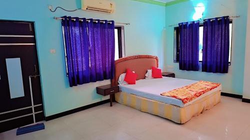 Schlafzimmer mit einem Bett mit blauen Wänden und lila Vorhängen in der Unterkunft Sai Dwarka Alibag Hotel in Alibag