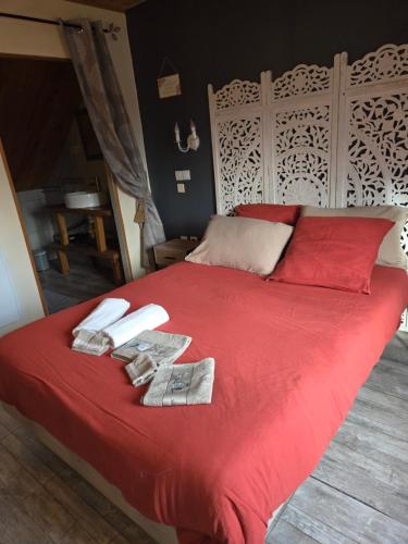 a red bed with red sheets and towels on it at La mare aux canards in Châteauvieux