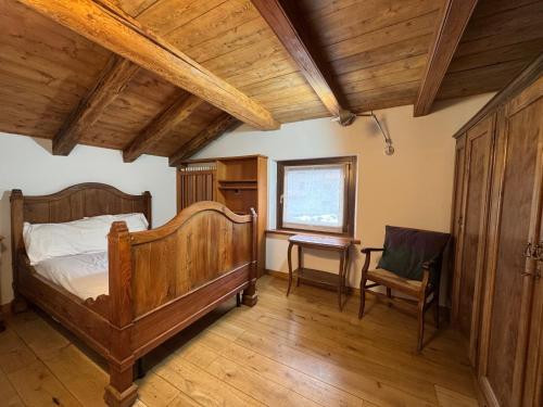 a bedroom with a wooden bed and a chair at We Are 4810 LA CORDE D'ESCALADE in Courmayeur
