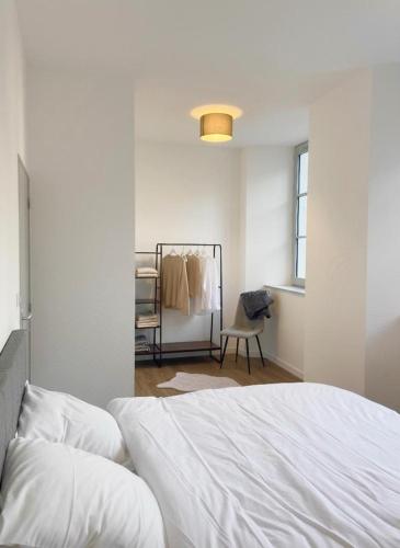 een slaapkamer met een wit bed en een stoel bij Appartement Du Lot in Entraygues-sur-Truyère